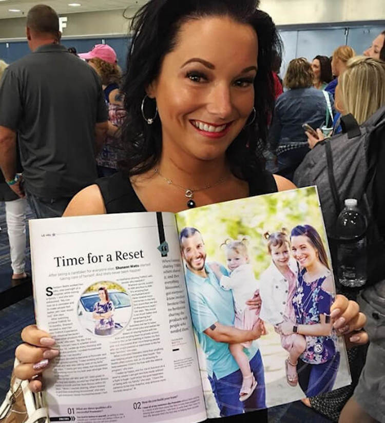 Shannan sosteniendo una revista con un reportaje que le hicieron a su familia feliz
